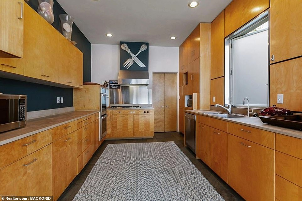 Kitchen goals: A curved wall separates the dining area from the massive kitchen, featuring chic wooden cabinets with concrete countertops and stainless still appliances